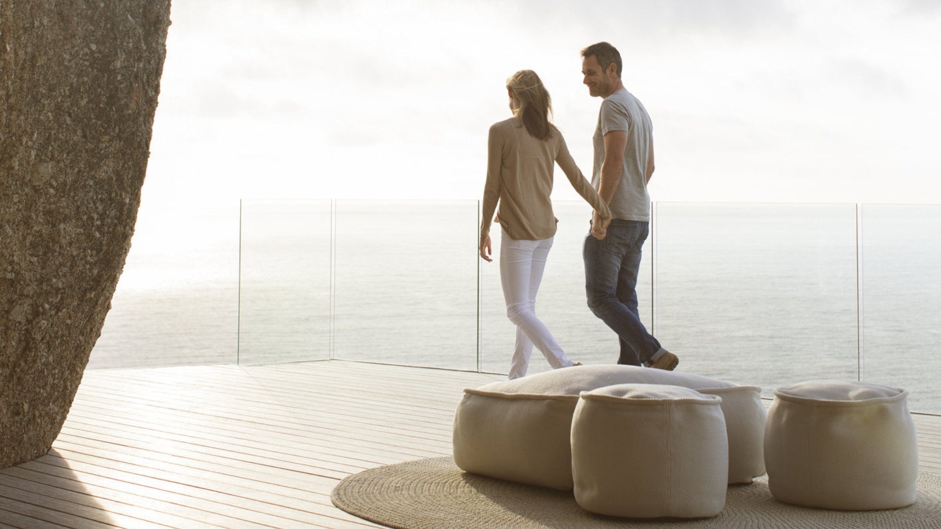 Coppia su terrazza vista mare con pavimentazione in legno composito e pouf da esterno