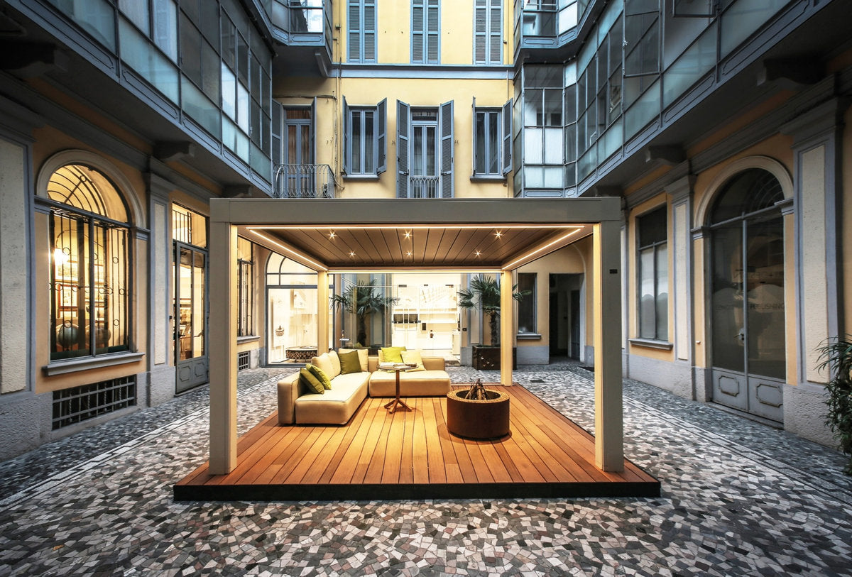 Spazio outdoor in cortile milanese con pavimentazione in legno per esterni e struttura autoportante con illuminazione integrata.