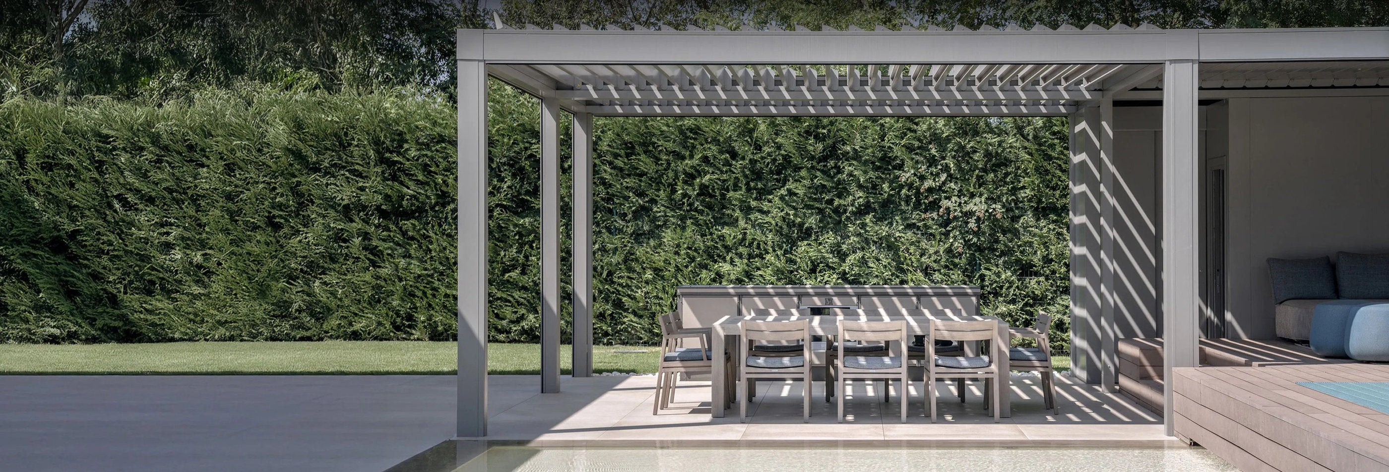 Pergola bioclimatica installata in giardino con zona pranzo coperta, esempio di posa professionale eseguita da Domotea a Milano e nord Italia