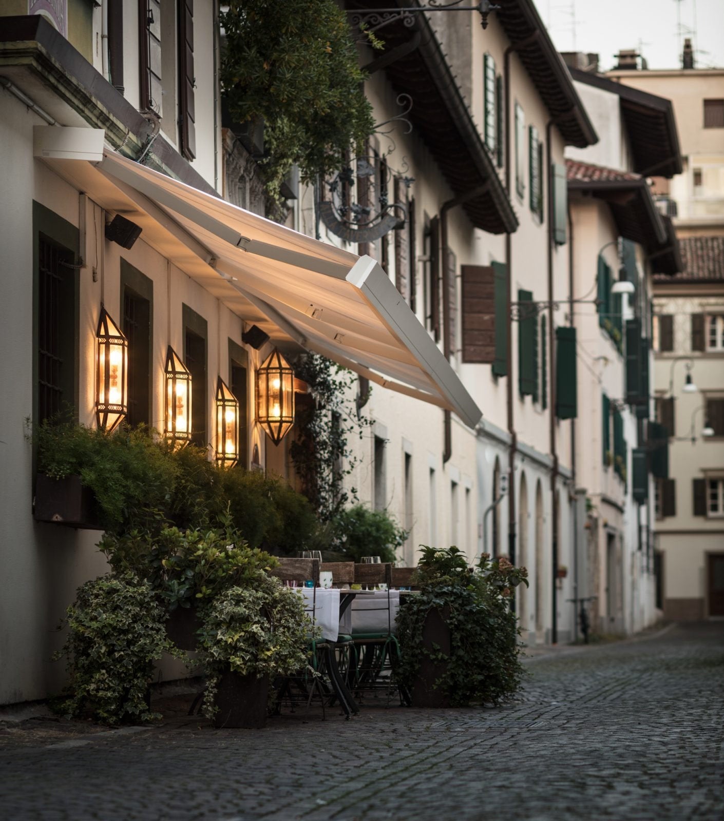 Tenda da sole a bracci su facciata di edificio storico con dehors elegante, esempio di intervento su tende da esterno in ambito ristorativo