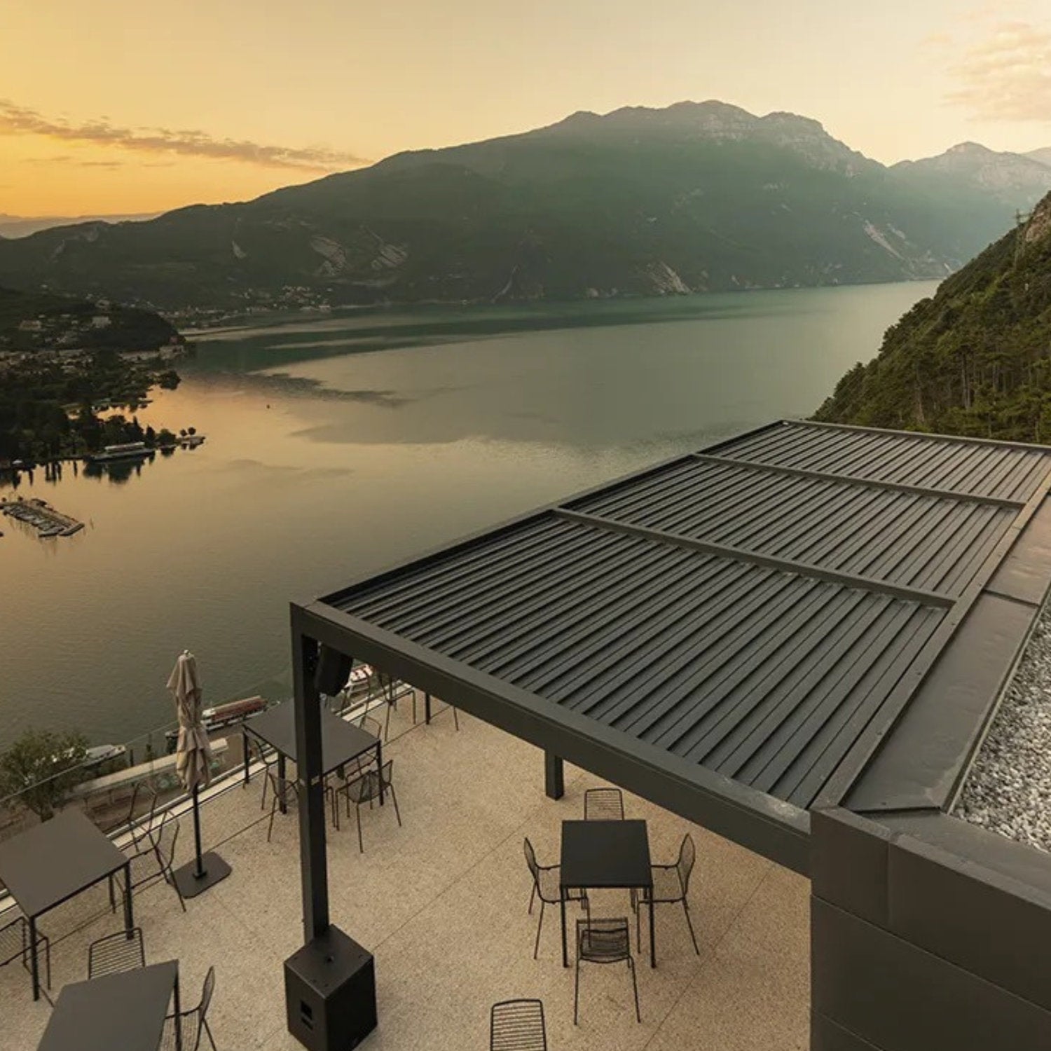 Pergola con lame chiuse installata su terrazza panoramica affacciata su un lago al tramonto