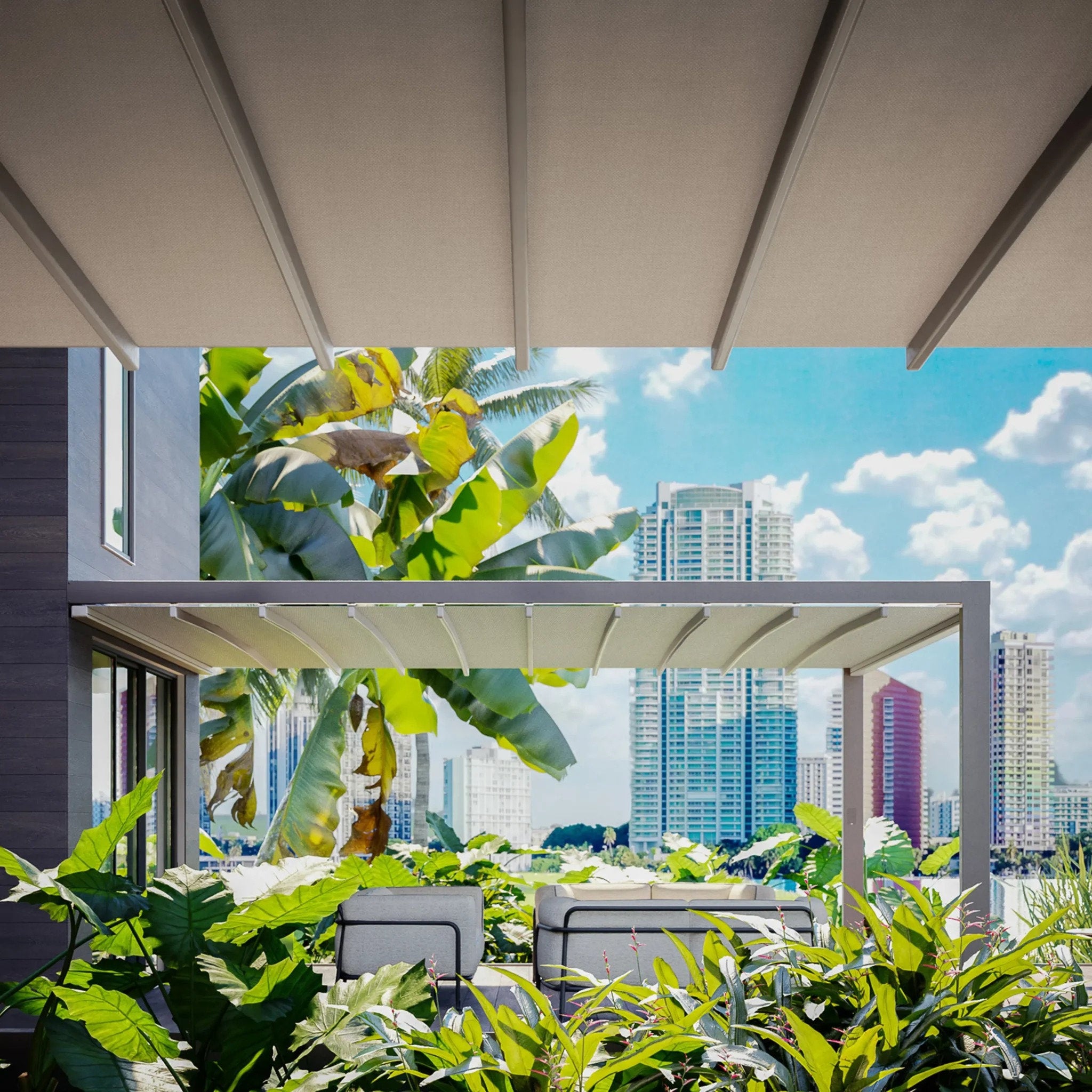Pergola con copertura in tessuto installata su terrazza circondata da vegetazione tropicale, con skyline di grattacieli sullo sfondo.