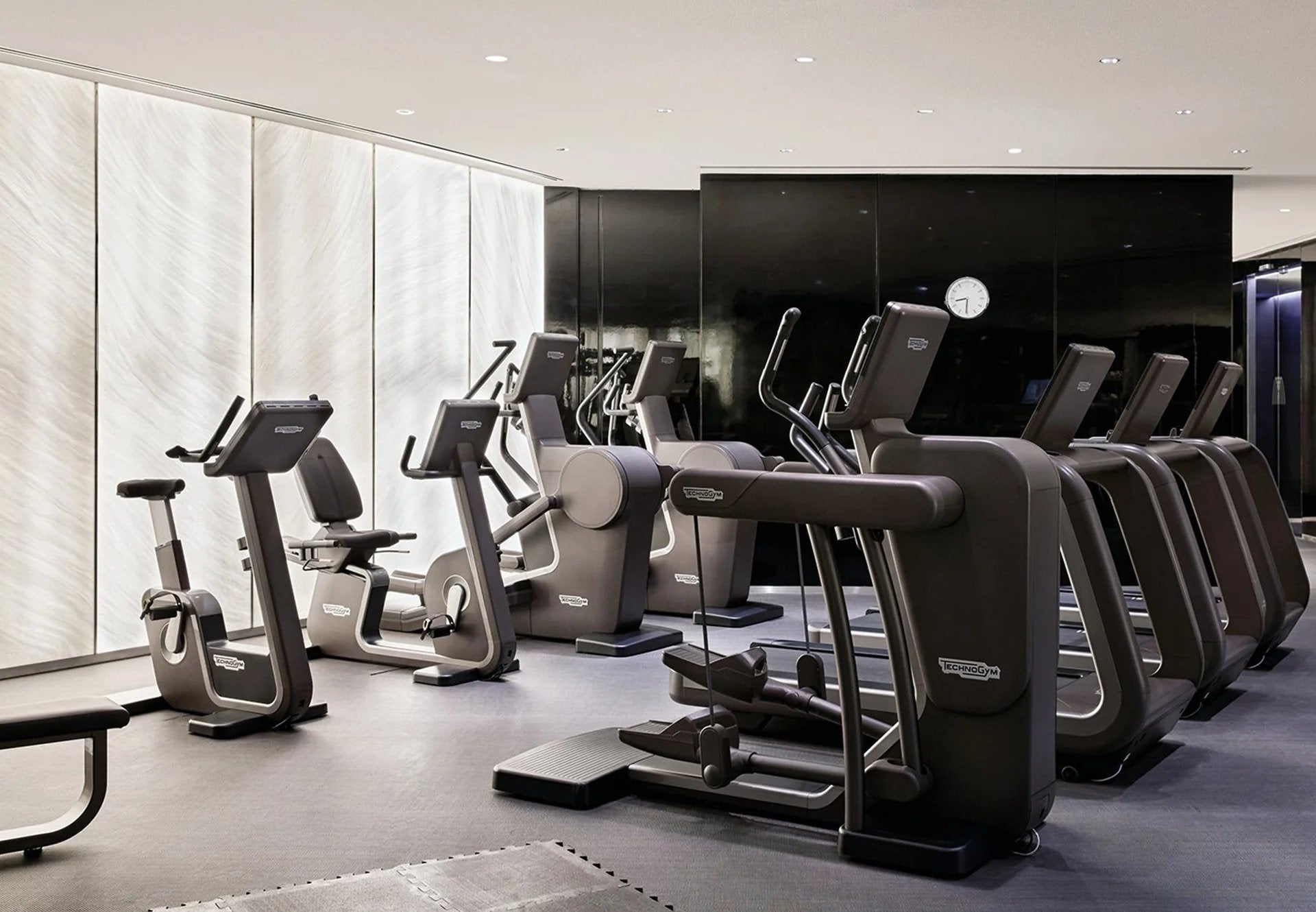 Palestra con attrezzature Technogym e parete vetrata schermata da tende a pannello in tessuto tecnico – Domotea Milano