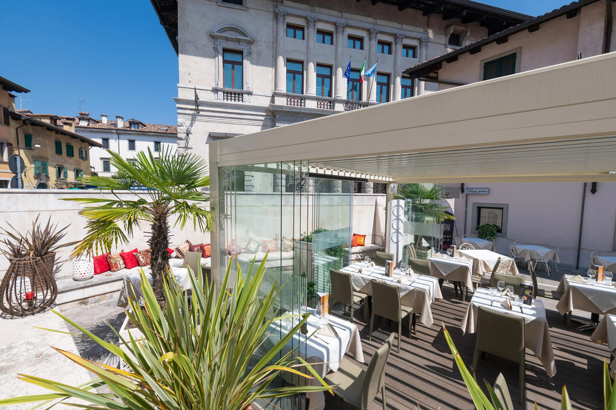 Tavoli e sedie nel dehors di un ristorante sotto una pergola Pratic