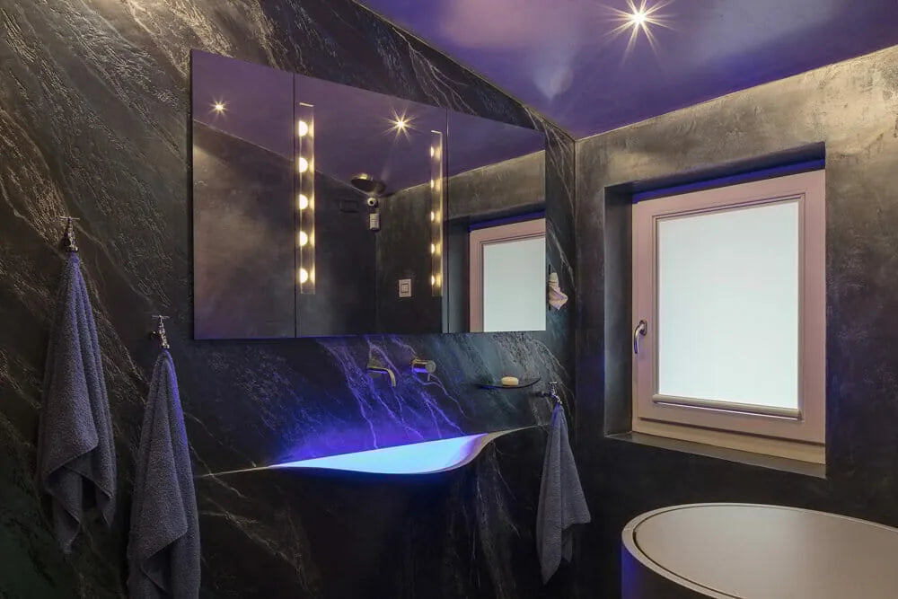 Tenda a vetro Nano Resstende sulla finestra di un bagno con rivestimenti scuri.