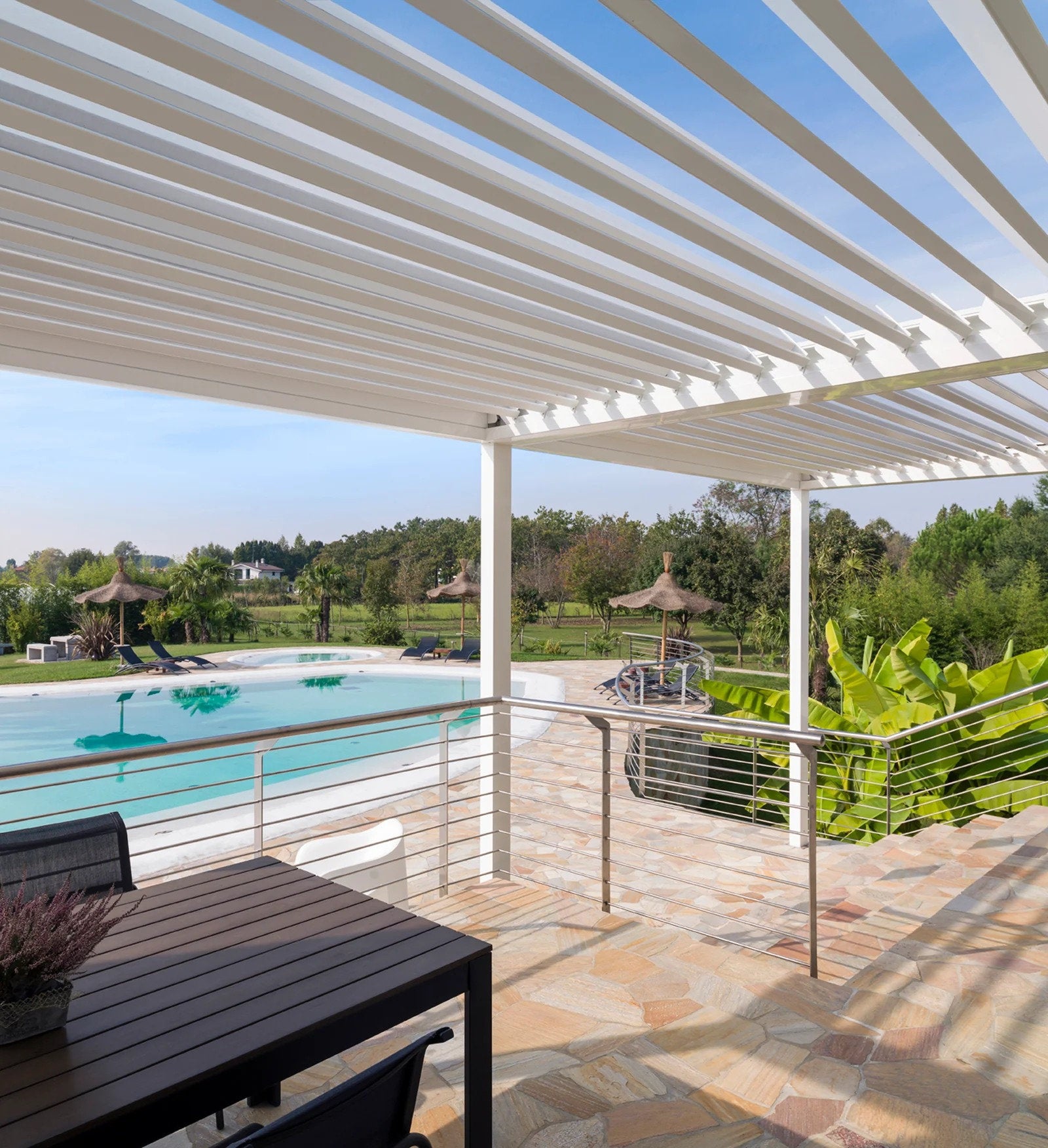 Pergola bioclimatica bianca installata a bordo piscina in contesto residenziale, esempio di schermatura solare che rientra nell’Ecobonus 50%