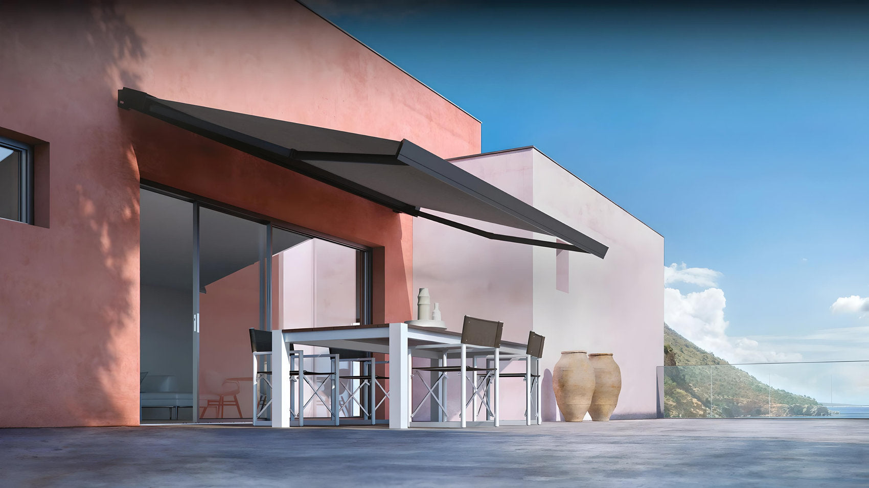 Tenda da sole a bracci installata su facciata moderna rosa, ombreggia un terrazzo con vista panoramica sul mare – Domotea Milano.