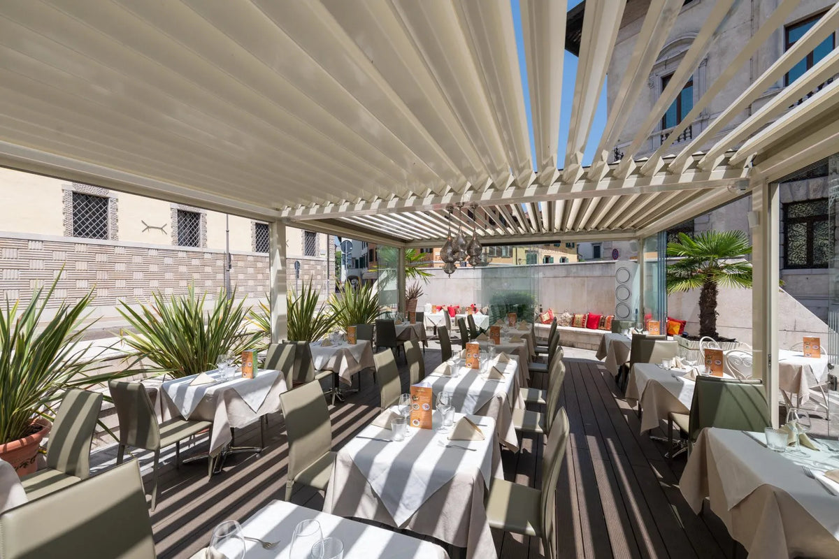Tavoli di un ristorante sotto una pergola bioclimatica Pratic