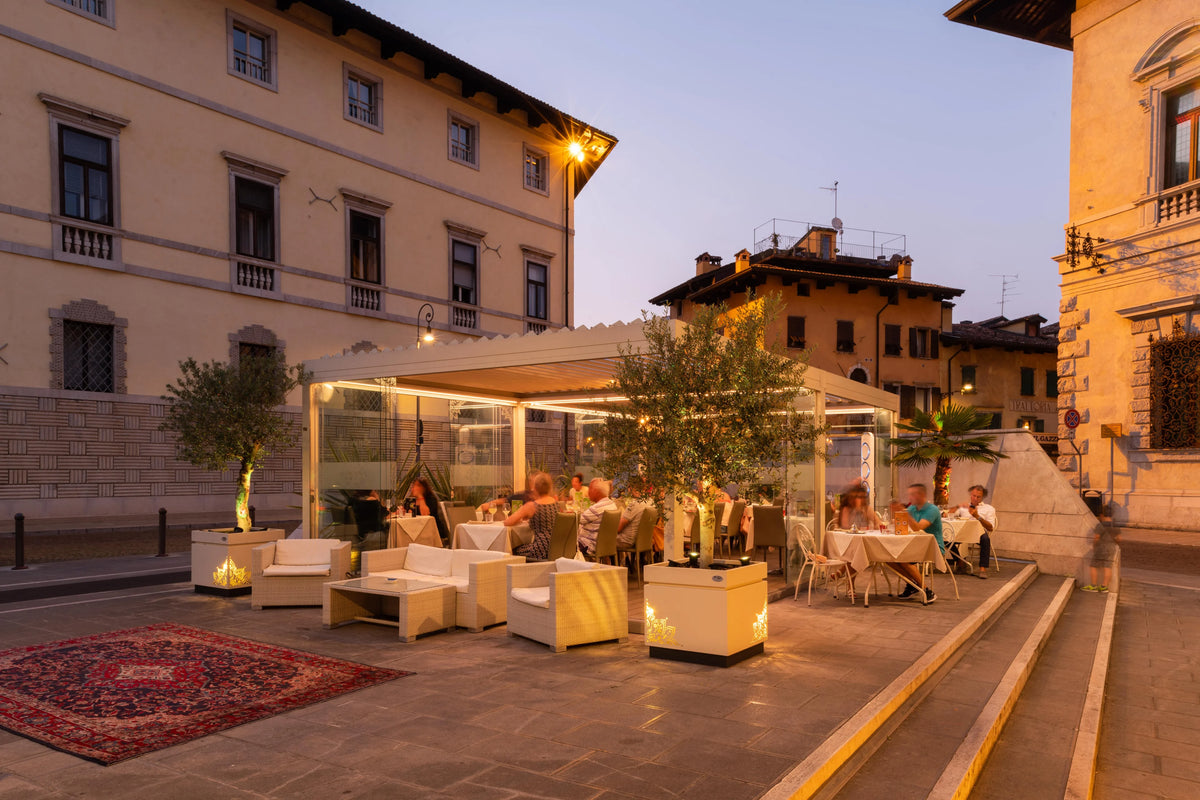 Dehors di un ristorante con pergola Pratic illuminata al tramonto